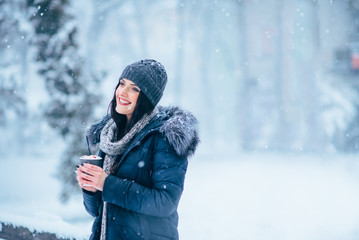 Young pretty girl with a glass of coffee in her hands in winter time.