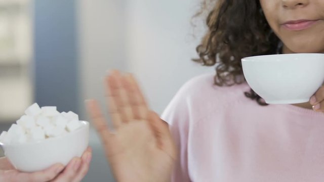 Mixed race female drinking green tea and refusing sugar, dieting and health
