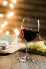 glass of red wine with french cheese and delicatessen in restaurant wooden table with romantic dim light and cosy atmosphere
