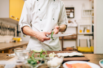 Male cook hands closeup, making sushi rolls