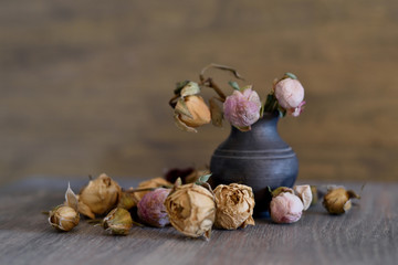 tender withered flowers in old beautiful vase on wooden background