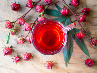 Cup of hot  roselle tea with fresh roselle fruit in top view on wooden table  for healthy herbal drink concept.