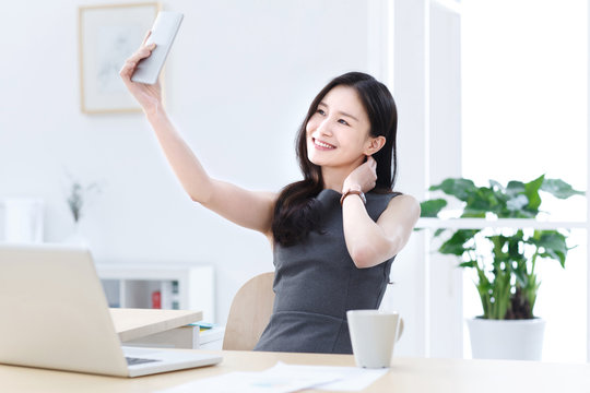Young business woman using mobile phone self timer