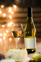 glass of white wine with french cheese and delicatessen in restaurant wooden table with romantic dim light and cosy atmosphere