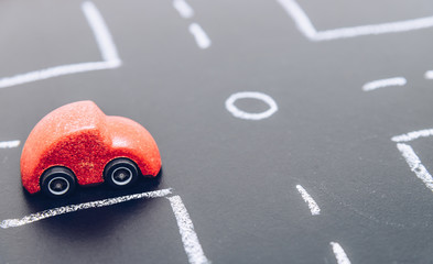 Red wooden car toy stop on crossroad on chalk board