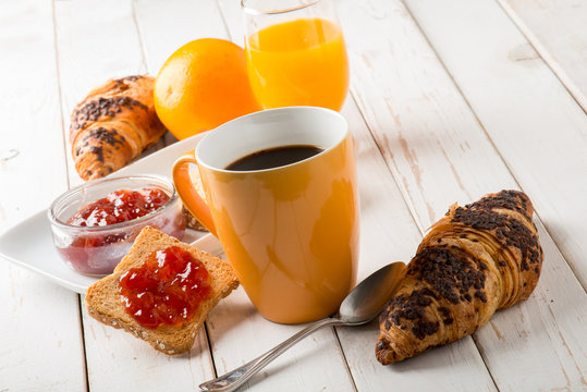 croissant  mug of coffee orange juice and toast with jam