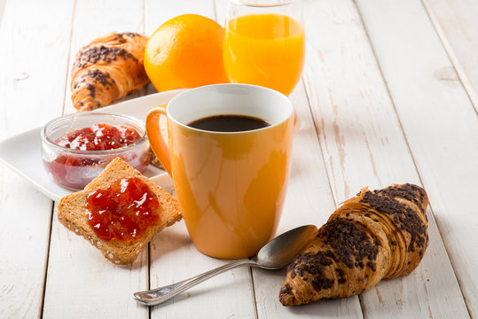 croissant  mug of coffee orange juice and toast with jam