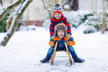 Fototapeta na wymiar Two little kid boys having fun sleigh ride in winter