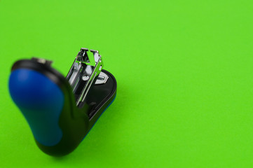 One new black and blue stationery stapler on green background