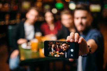 Fun friends makes selfie on phone in a sport bar