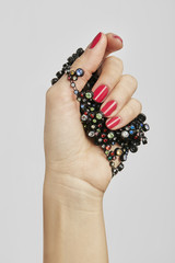 HAND WITH RED NAIL POLISH HOLDING JEWELS