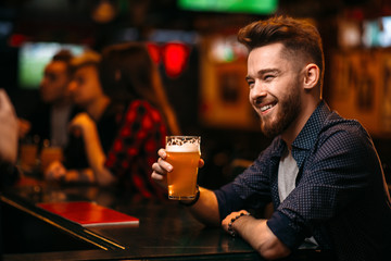 Man drinks beer at the bar counter in a sport pub
