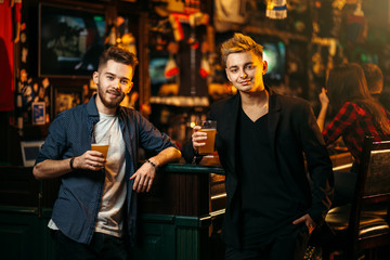 Fototapeta premium Men raised their glasses with beer in a sport pub