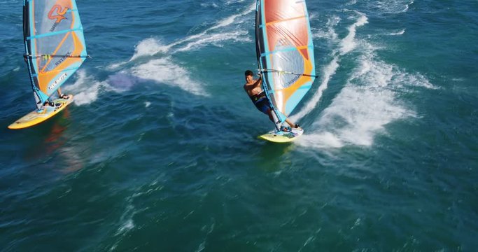 Cinematic aerial view of windsurfers sailing across the ocean