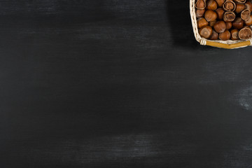 Hazelnuts in a basket on a black board.
