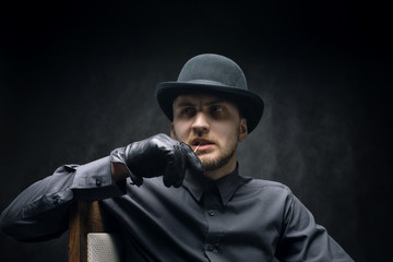 Pensive man in a hat and toothpick in his mouth, against a dark background