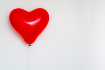 Red heart shaped balloon on a string isolated on white