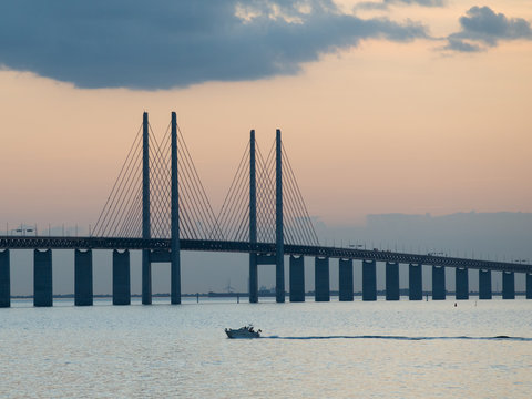 Motorboat cruising at dusk in Oresund towards Oresund Bridge viewed from Limhamn in Malmo, Sweden