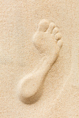 A single foot print imprinted in the sand on the beach