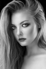 Fototapeta premium Monochrome closeup beauty portrait of young beautiful blond girl with long straight hair with natural makeup. Hairstyle, skincare and cosmetics concept