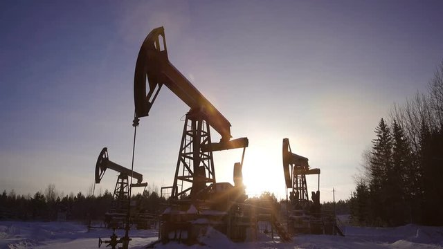 Pumpjack, oil pumping unit against a beautiful forest landscape