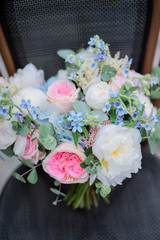 Bouquet of white and pink flowers stands on grey chair on the streets