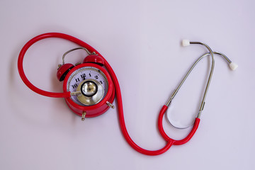 A red stethoscope kit and red bell clock.Time is important in life