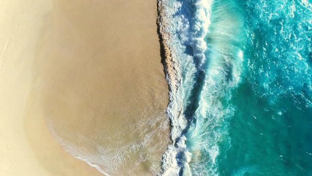 Aerial view waves break on white sand beach. Sea waves on the beautiful beach aerial view drone 4k shot. 