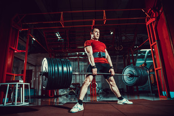 Muscular fitness man doing deadlift a barbell in modern fitness center. Functional training. Snatch...