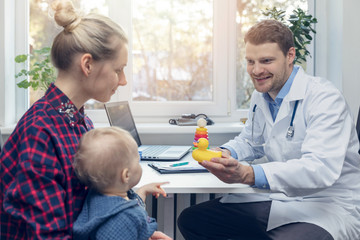 doctor gives to child a duck toy during a medical visit