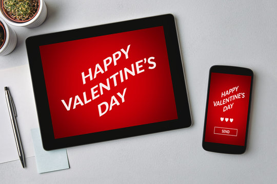 Valentine's day concept on tablet and smartphone screen over gray table. All screen content is designed by me. Flat lay