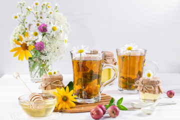  A healthy Cup of  herbal tea, a jar of honey and wild flowers. On white background