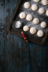 Homemade almond cookies with sugar powder, with vintage sieve, on old oven tray over dark blue wooden table. Dark rustic style. Top view, space
