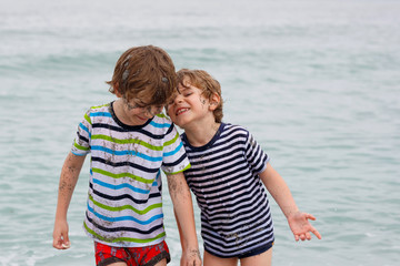 Two happy little kids boys running on the beach of ocean