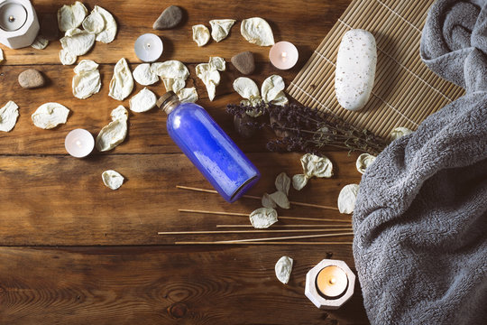 Image of a Gray Towel, Dried Rose Petals, Candles, Soap, Skin Lotion, Spa treatments on a wooden background. The concept of Spa Treatments and Saunas, Steam Baths.