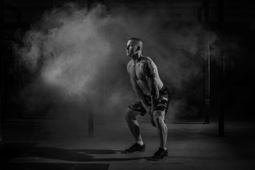 Fototapeta na wymiar Muscular male athlete pulls weight in the gym black and white filter