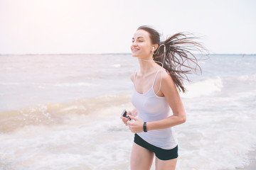 Fototapeta na wymiar Beautiful woman running during sunset. Young fitness model near seaside. Dressed in sportswear.