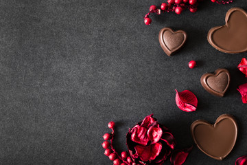 Chocolate hearts with dried red rose's leaves on the dark table. Enjoying a candies. Valentine's day concept. Mock up for candies offers as advertising or other ideas. Empty place for a text.