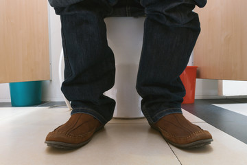 Man sitting on toilet bowl.