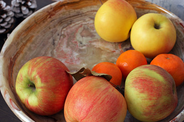 Apples and tangerines on a marble plate close up	