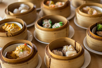 The set of Chinese steamed food in bamboo round flat basket served on the table , the food made from meat such as pork shrimp or fish and can be seen things like these in restaurant. 