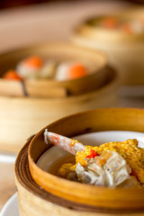 The set of Chinese steamed food in bamboo round flat basket served on the table , the food made from meat such as pork shrimp or fish and can be seen things like these in restaurant. 