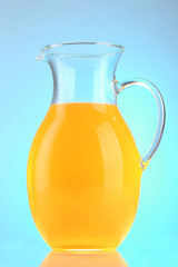 Jug of orange juice on blue background