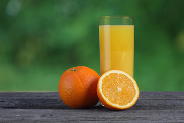 Glass of orange juice and oranges on wooden table