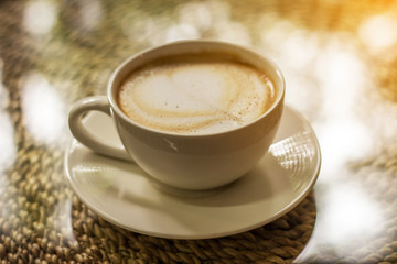 The hot coffee in the ceramic cup on the wooden table in restaurant.