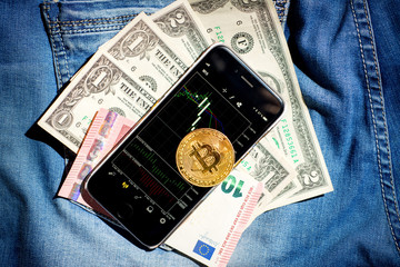 Coin bitcoin with phone on blue jeans background