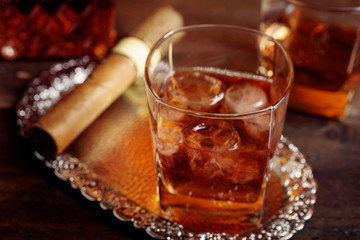 Glass of  whiskey and cigar on old wooden table.