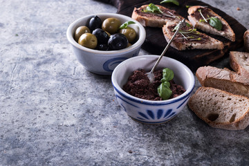 Green and black olives in tin cans ,fresh bread,bottle of olive oil on old wood background. italian food concept