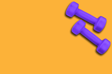 Fototapeta na wymiar Pair of dumbbells of color ultra violet 18-3838 on a yellow background
