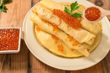 Pancakes with red caviar on plate. Russian cuisine. Maslenitsa.
